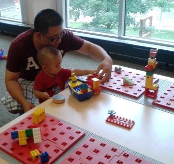 A parent plays with their child at a table.